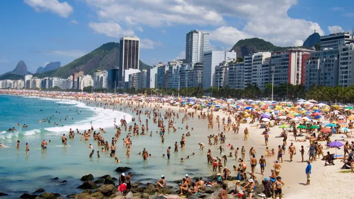 Praia de Copacabana é boa para banho no verão Praia de Copacabana com águas claras e pessoas se divertindo, ideal para banho.