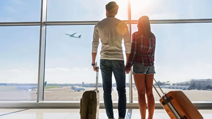 Pessoa planejando viagem com milhas a&eacute;reas usando laptop e blocos de notas